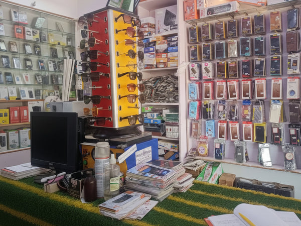 Display of sunglasses and electronic devices in a store with shelves and products.
