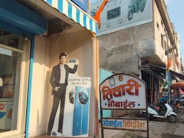 Small shop with a signboard in a foreign language, surrounded by advertisements and a scooter.