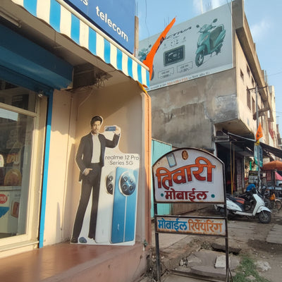 Small shop with a signboard in a foreign language, surrounded by advertisements and a scooter.