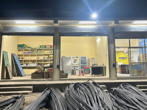 Storage unit with shelves and items, illuminated by lights, with a pile of metal sheets in front.