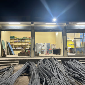 Storage unit with shelves and items, illuminated by lights, with a pile of metal sheets in front.