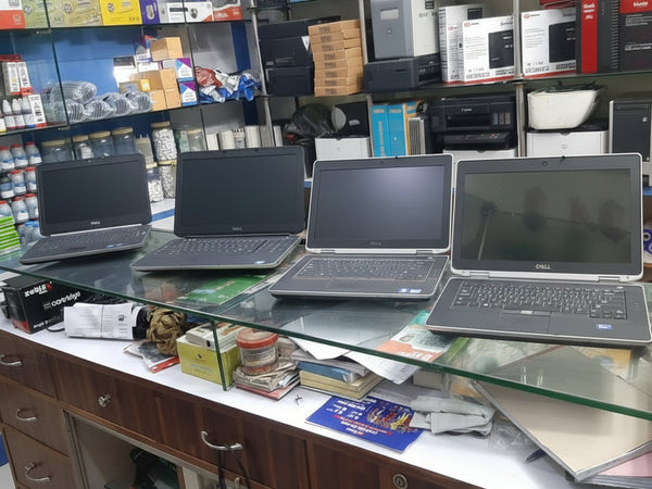 Four laptops on a glass table with a store shelf in the background