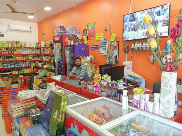 Interior of a small convenience store with orange walls and various products on shelves.