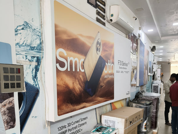 Electronics store interior with air conditioners and a large advertisement on the wall.