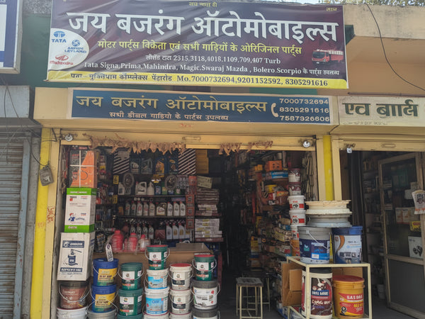 Automobile parts store with a large signboard displaying contact information and product categories.