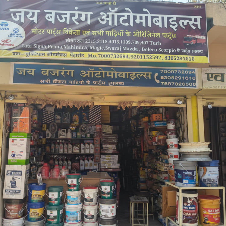 Automobile parts store with a large signboard displaying contact information and product categories.