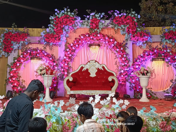 Decorated stage with floral arrangements and a red chair, likely for an event or celebration.