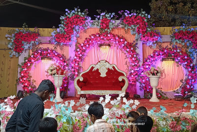 Decorated stage with floral arrangements and a red chair, likely for an event or celebration.