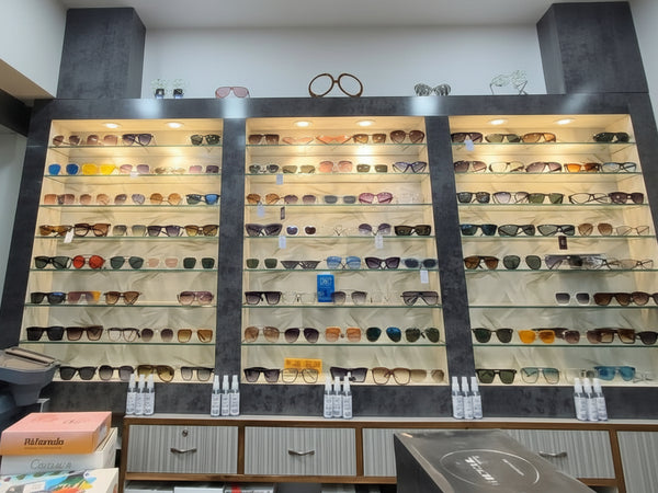 Display of sunglasses and boxes in a store with a white ceiling.