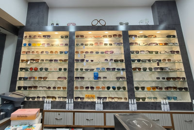 Display of sunglasses and boxes in a store with a white ceiling.